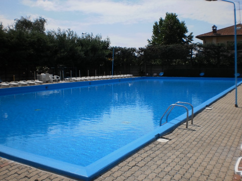 Angolo della piscina principale con scaletta e bordo pavimentato