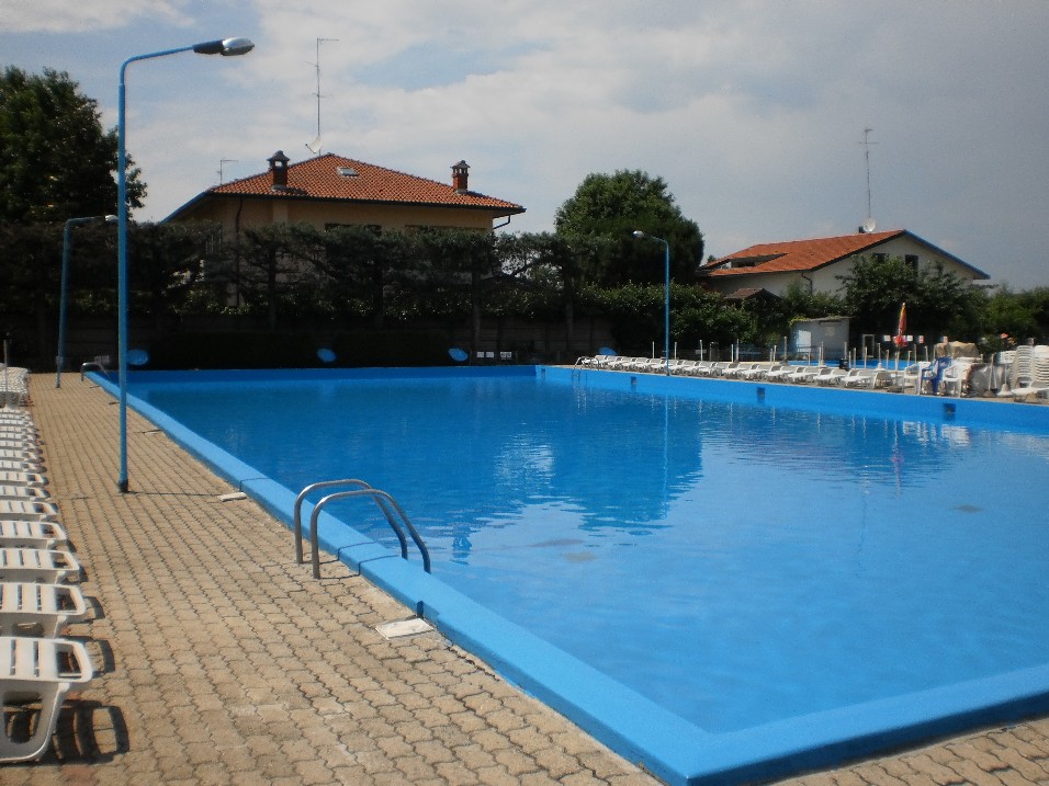 Piscina principale vista dal bordo, con scaletta e file di lettini